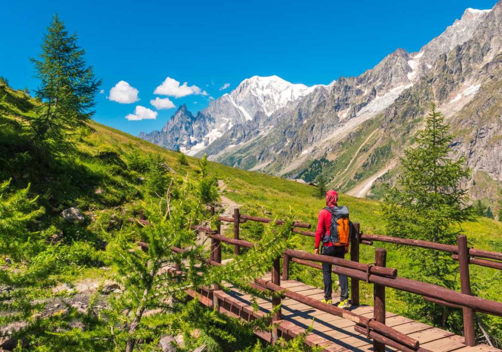 Wanderin läuft über eine Holzbrücke Richtung Pfad am Mont Blanc