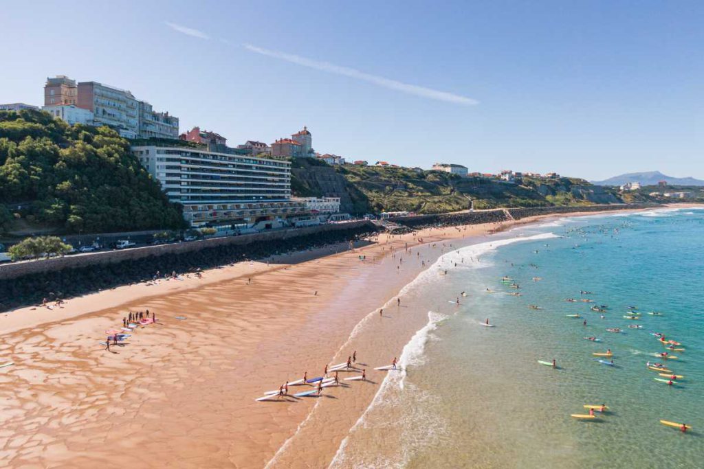 Biarritz ist auch ein Surferparadies Aufnahme einer Drohne des Baskenstrands mit vielen Surfern, die im flaschen Wasser auf eine Welle warten.