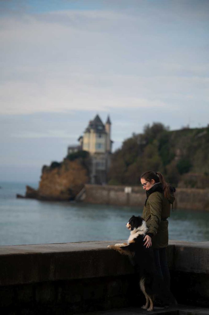 Idyllische Spaziergang am, Strand oder der rauen Natur des Baskenlandes sind überall möglich Frau mit Ihrem Hund auf der Promenade Richtung Biarritz aufs Meer blickend.