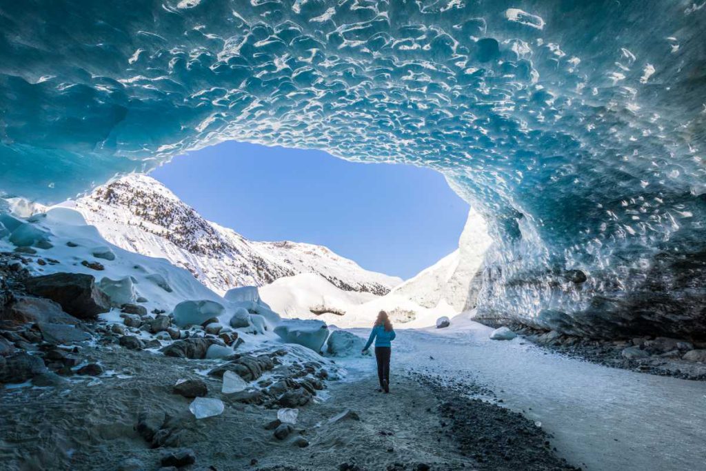 Bezaubernde Orte als Ziel der Winterwanderung. Nicht immer muss es nur die Aussicht sein. Frau steht in der Eishöhle von Morteratsch Glacier, Grisons