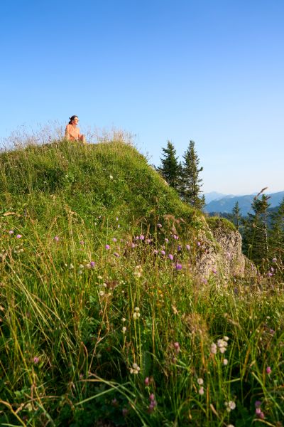 Nagelfluh-Bergkette bei Oberstaufen, Bayern, Deutschland hübsche ältere Frau wandert im warmen Morgenlicht und genießt die spektakuläre Aussicht über die Allgäuer Alpen
