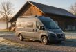 Graues Wohnmobil steht vor einer Scheune und trotzt den eisigen Temperaturen