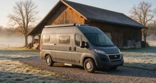 Graues Wohnmobil steht vor einer Scheune und trotzt den eisigen Temperaturen